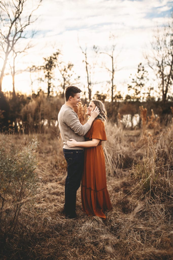 Family Photographer - Man and woman lovingly embrace in a dry field